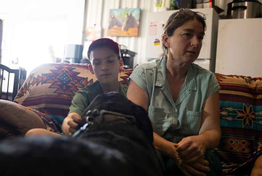 Zach Lindeen pets Ruger, one of Romana Harding’s dogs, as his listens to his mom speak about how cannabis quiets his seizures during an interview on Tuesday, July 29, 2025, outside of Midway, TX.